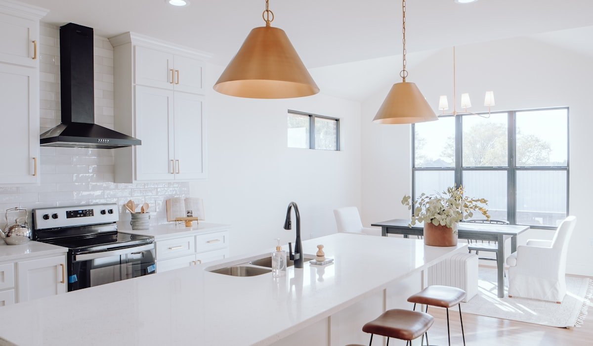 Bright Winnipeg kitchen renovation with brass cone pendants, white shaker cabinetry, and leather counter stools