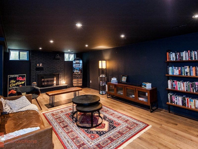 Finished Winnipeg basement with hardwood flooring, fireplace, dark walls, and warm mid-century furnishings
