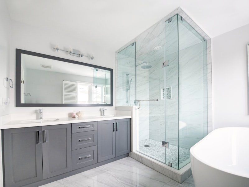 Modern Winnipeg bathroom renovation with grey vanity, marble walk-in shower, and frameless glass enclosure