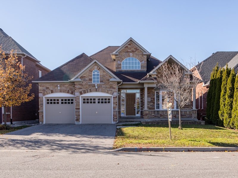Winnipeg residential exterior with stone and brick siding, double garage, and dormered roof