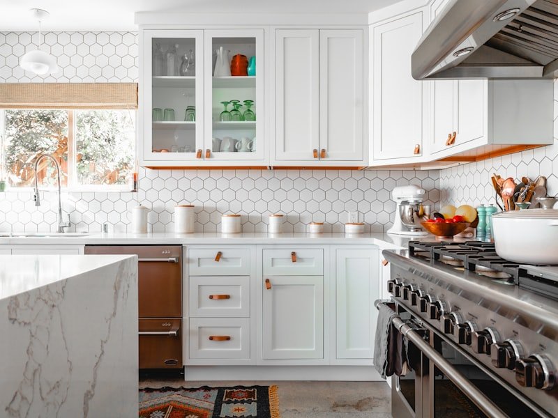 Renovated Winnipeg kitchen with white shaker cabinetry, hexagon tile backsplash, leather pulls, and butcher-block accent